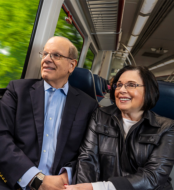 Senior couple holding hands while riding a transit train
