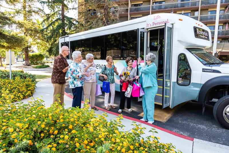 Residents standing with shopping bags, waiting for the community shuttle bus.