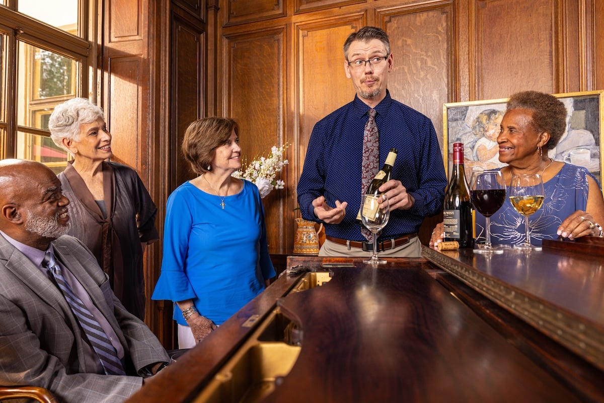 Residents gathered around piano with wine