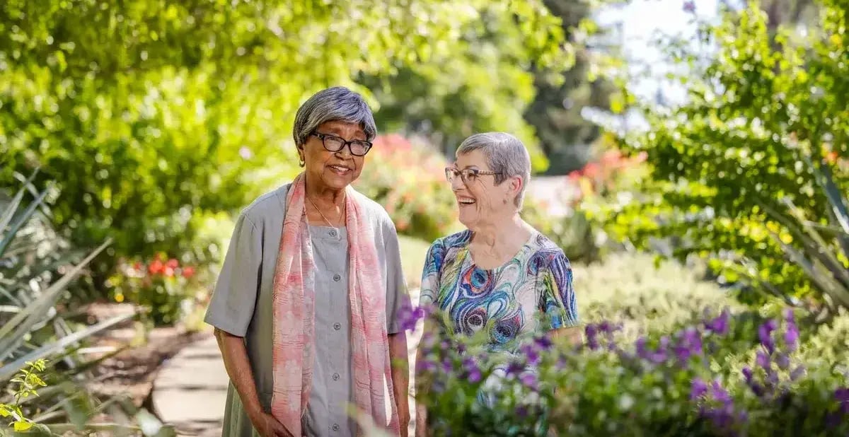 two women walking through a garden together