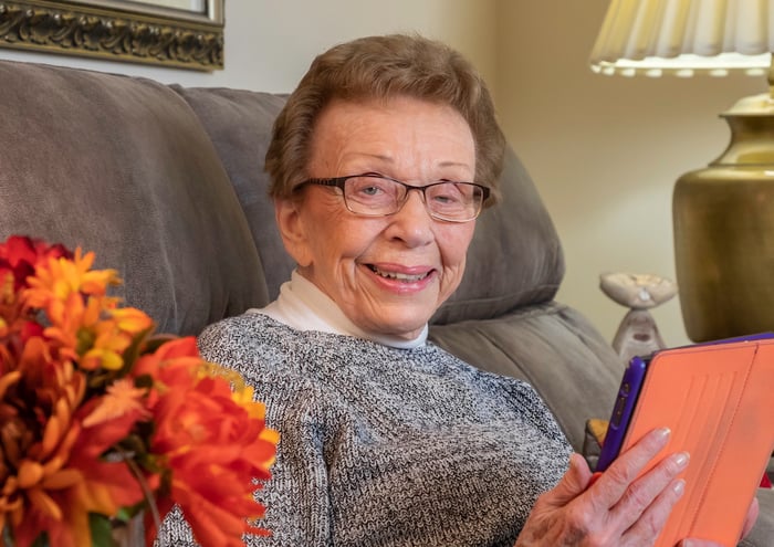 woman smiling on couch using ipad