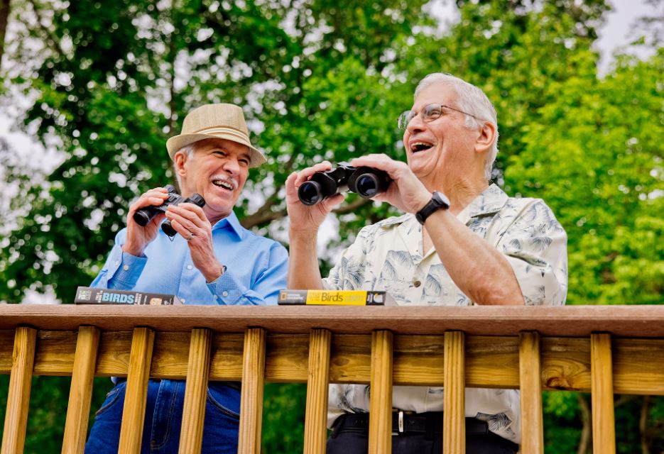 Two senior men outside birdwatching with binoculars
