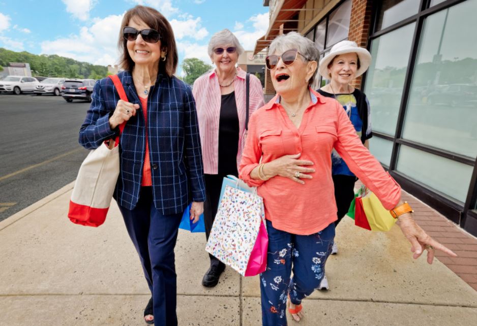 Group of four senior women walking outside with shopping bags
