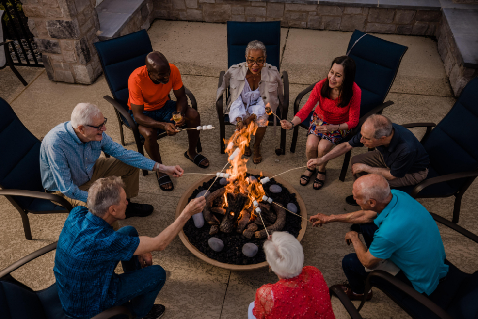 Group of seniors roasting marshmallows over an outdoor firepit