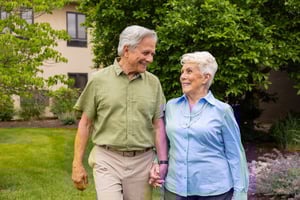 Senior couple holding hands and walking on the grounds of Spring Mill Pointe
