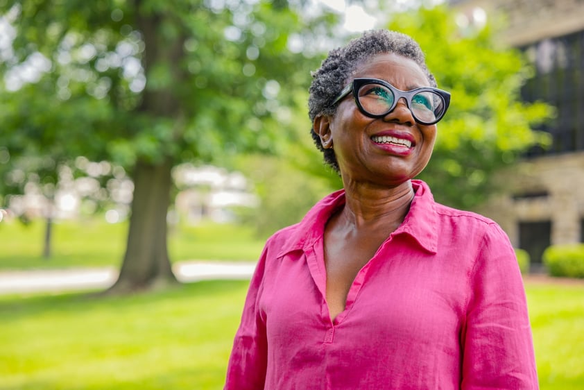 Smiling senior woman standing outside on the grounds of Spring Mill Pointe