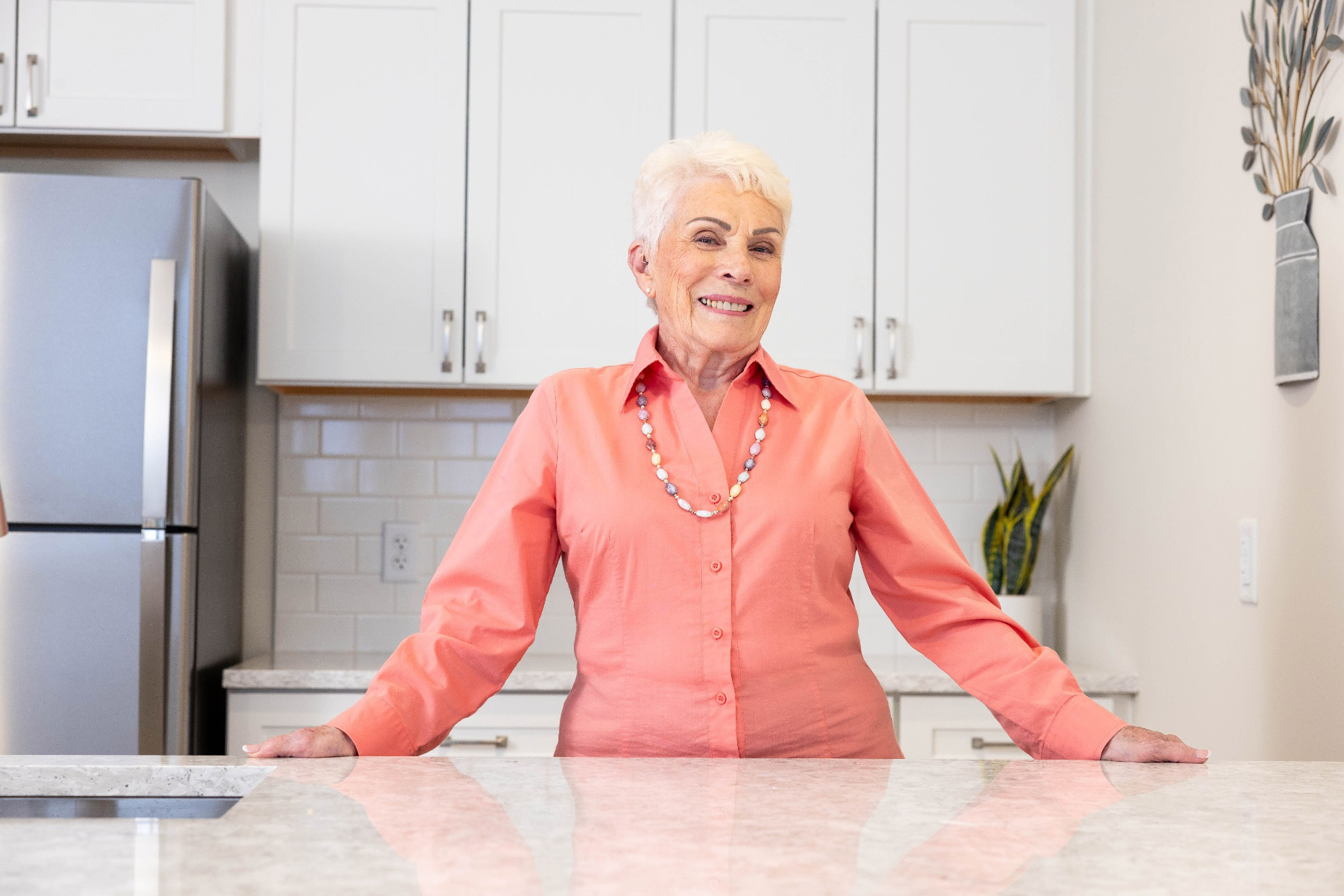 Smiling senior woman standing in the modern kitchen of her Spring Mill Pointe apartment