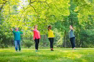 Female teacher leading a class of three senior women doing tai chi on the grounds of Spring Mill Pointe