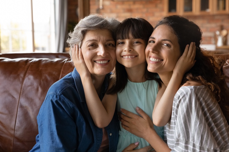 Three generations of women sitting on a sofa and smiling