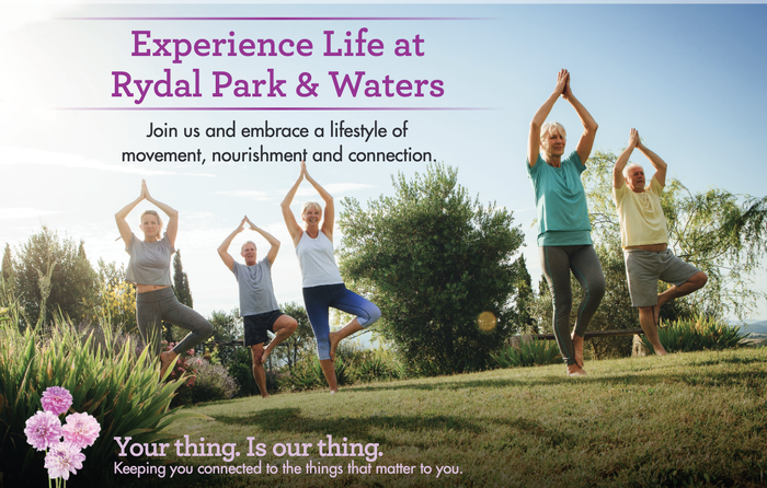 Five residents practicing yoga in tree pose on a grass lawn with trees and pink flowers nearby.