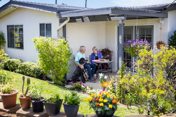 Senior couple sitting on their patio with their black poodle