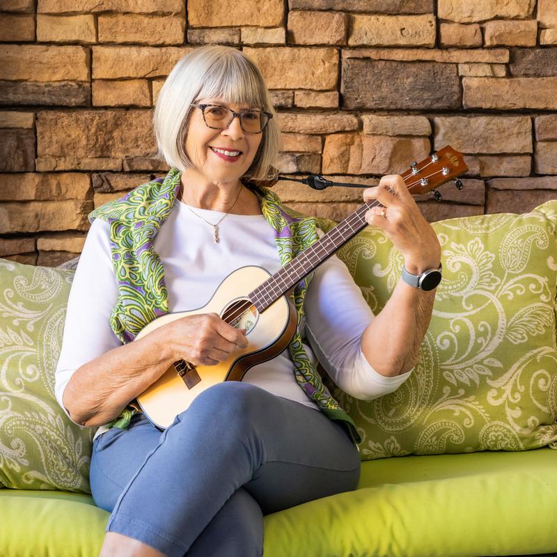 woman smiling on couch playing the ukulele