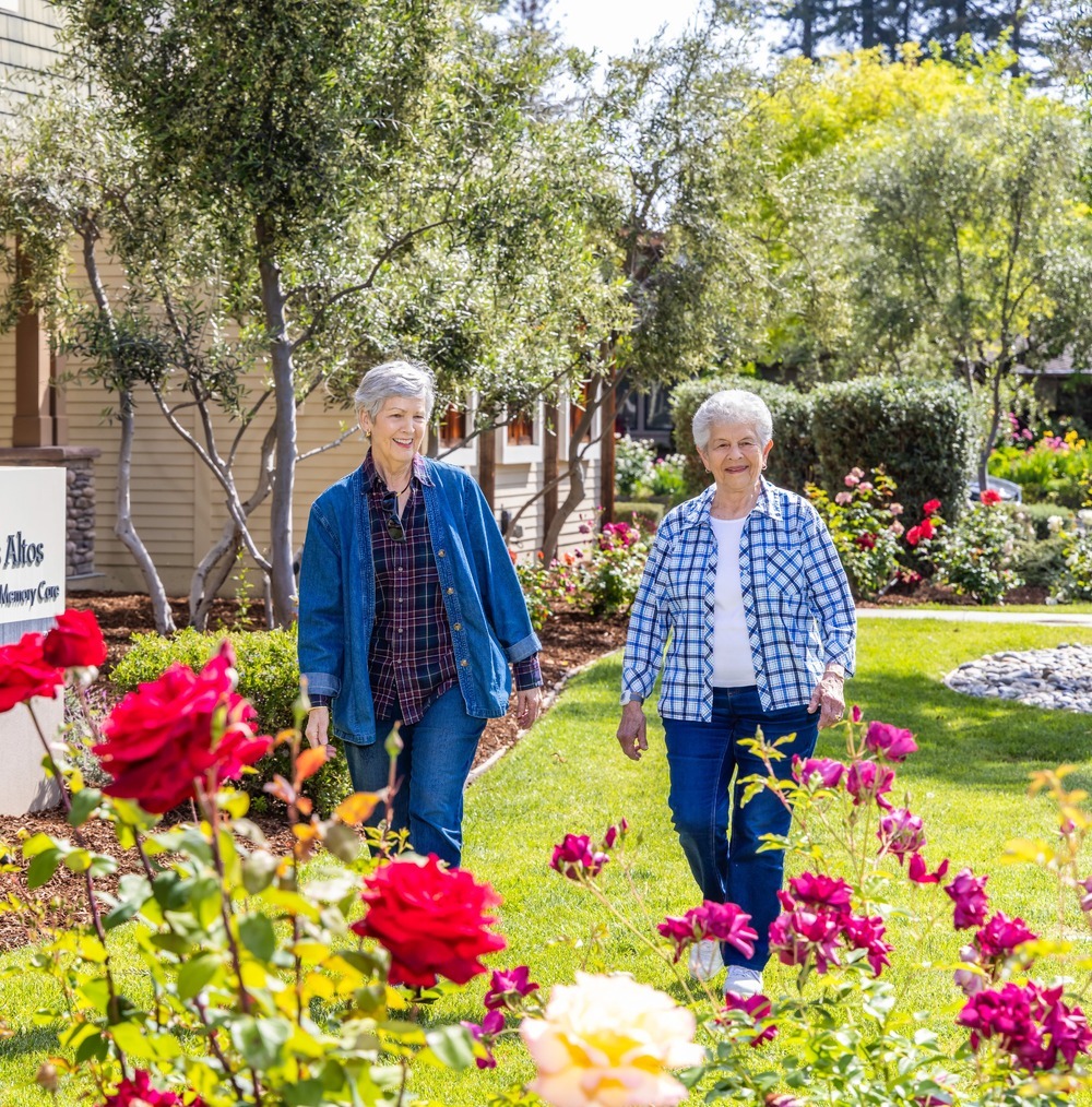 Two senior women walking in the garden at The Terraces at Los Altos