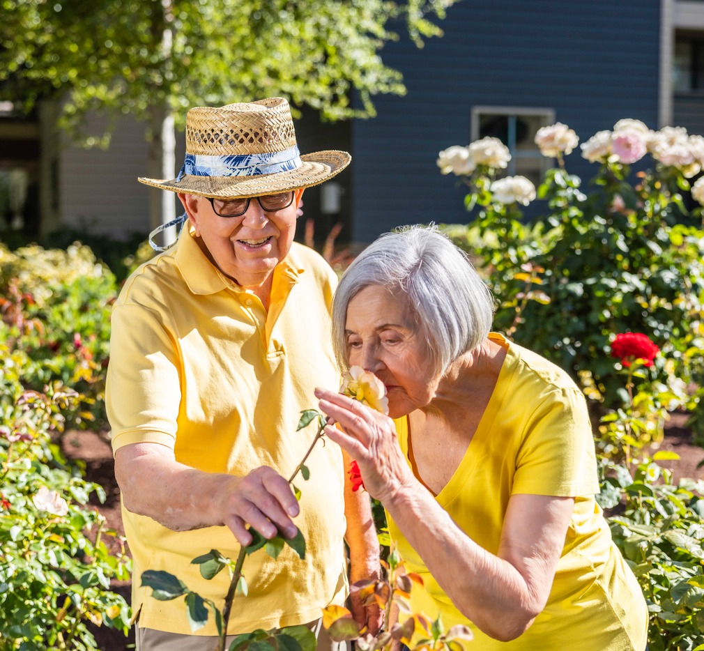Woman smelling a flower while standing next to a man