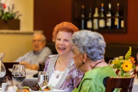Two residents laugh over dinner. 
