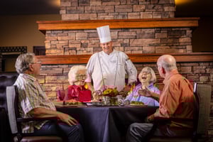 Chef chatting with a group of four seniors dining in The Terraces of Boise dining room