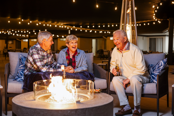 Three seniors sitting around a firepit