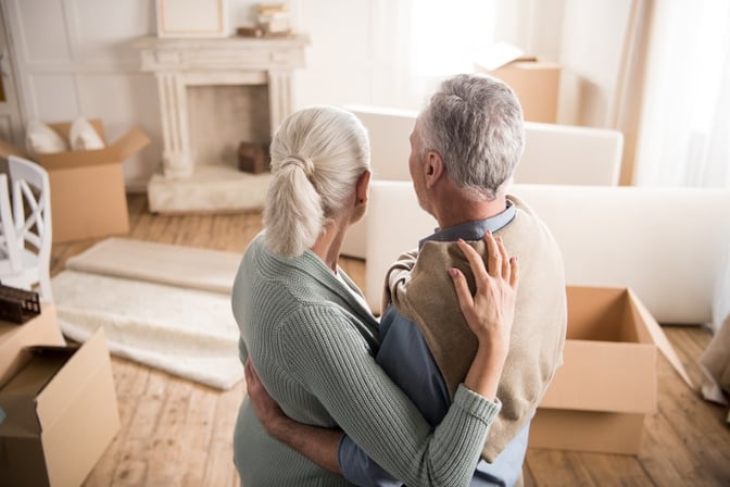 A couple embraces each other in a living room with moving boxes.