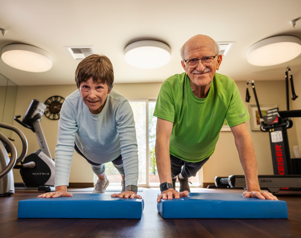 Senior man and woman holding a plank in the fitness center