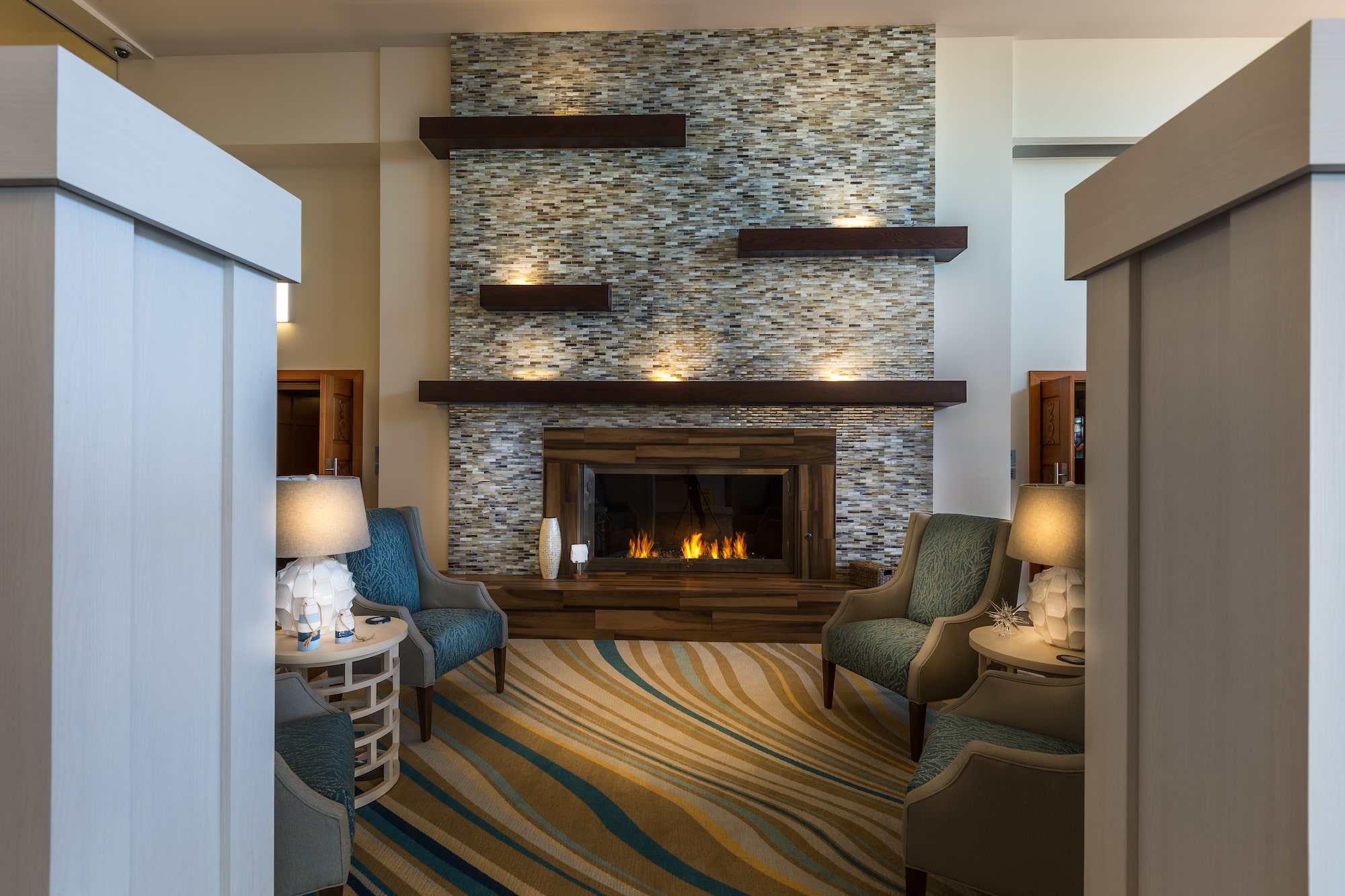 Cozy lounge with armchairs and a modern fireplace feature wall.