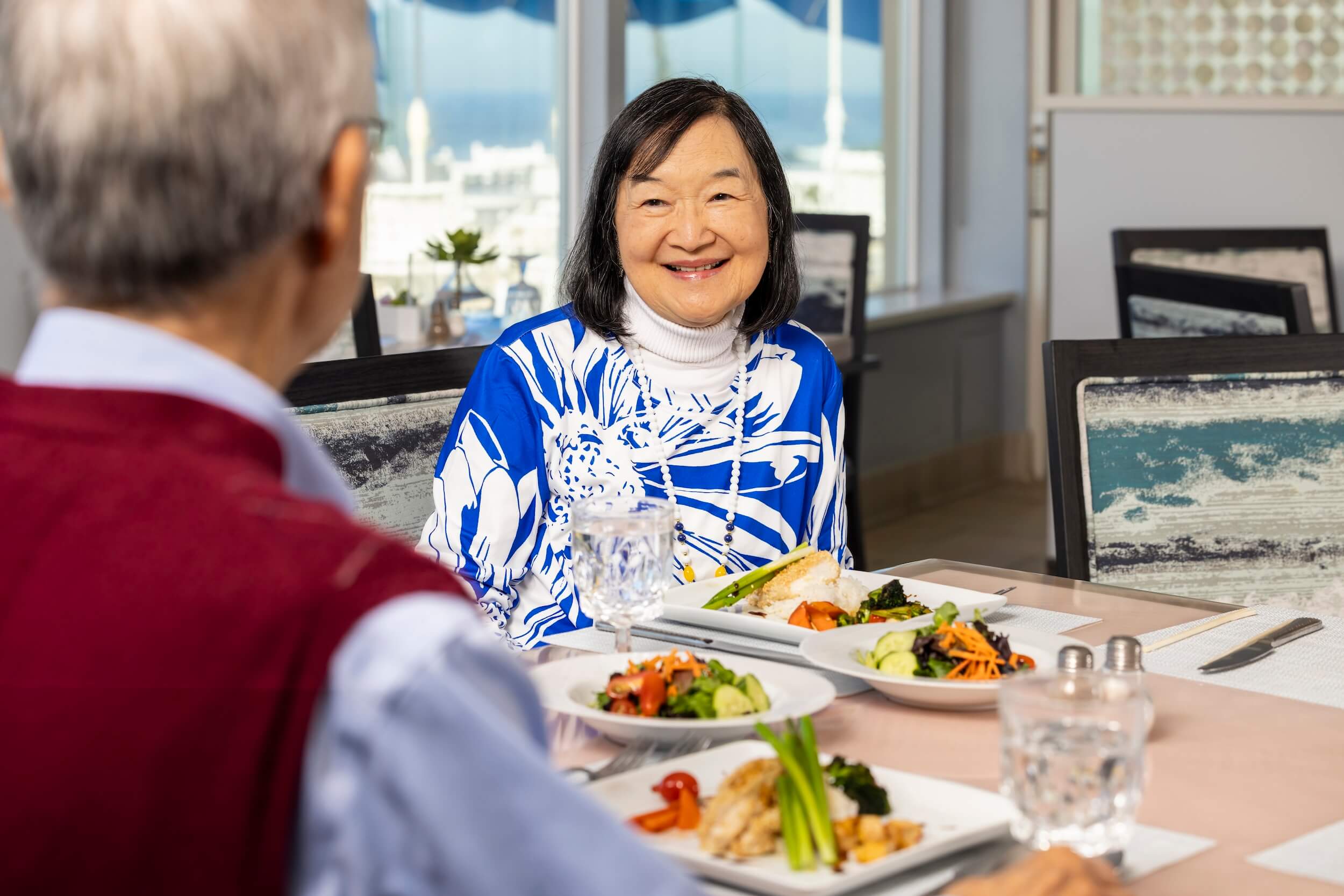 Older adults enjoying a meal together in a bright dining area.