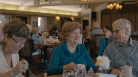 Kaye laughing with friends around the dinner table