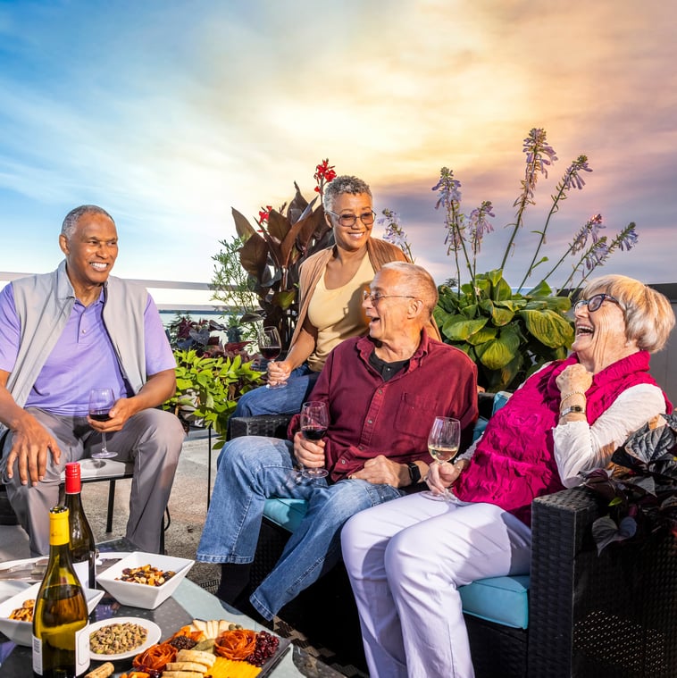 Judson Park residents laughing together on the rooftop patio with wine and snacks.