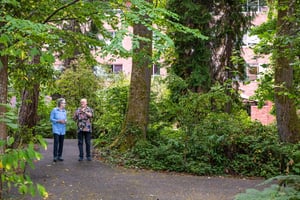 Residents walking together along a tree-lined path on the Judson Park campus, a HumanGood community.