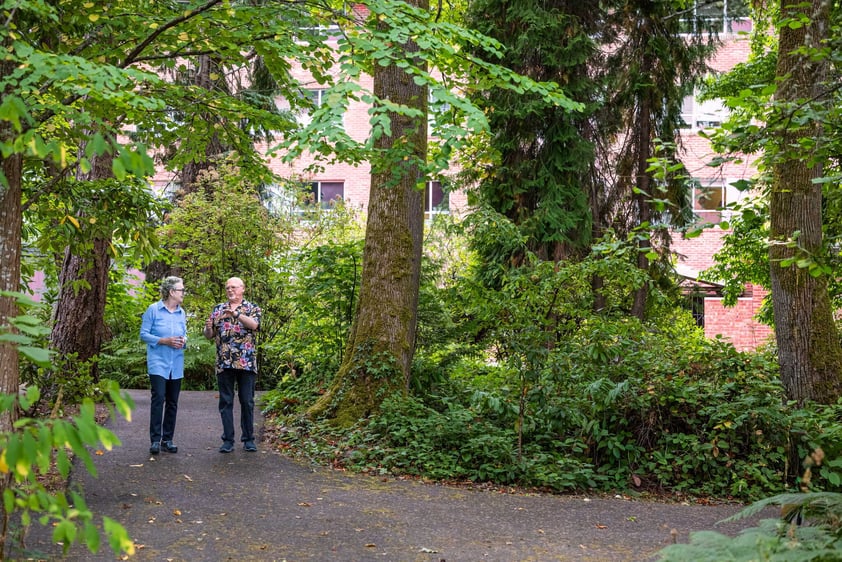 Residents walking together along a tree-lined path on the Judson Park campus, a HumanGood community.
