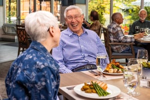 Residents laughing together at a dining table during a meal at Judson Park, a HumanGood community.