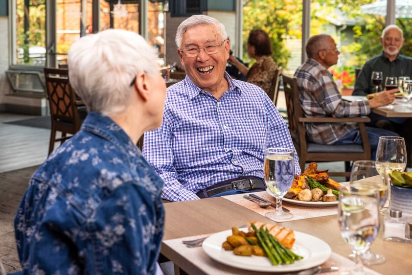 Residents laughing together at a dining table during a meal at Judson Park, a HumanGood community.