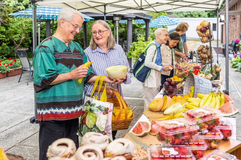 Residents selecting fresh fruits and vegetables at an outdoor market-style table at Judson Park, a HumanGood community.