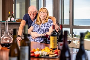 Residents smiling together at a table with wine and appetizers and scenic views at Judson Park, a HumanGood community.