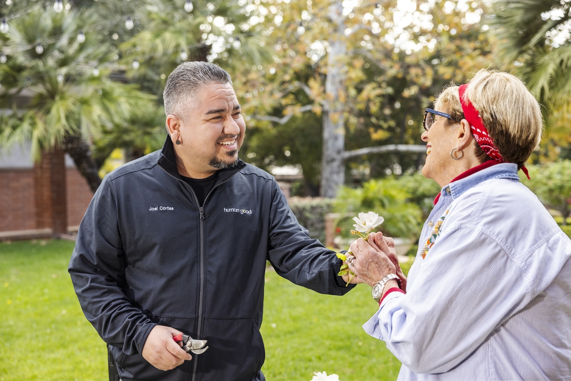 HumanGood team member offering a flower to a woman outdoors
