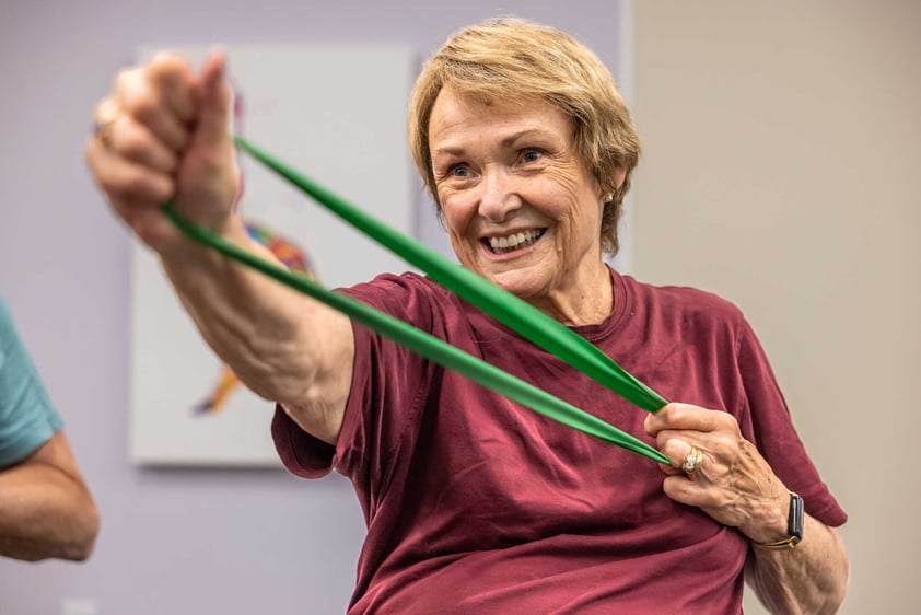 A resident stretching an exercise band during a fitness class