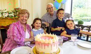 senior grandparents celebrating a birthday with their three grandchildren