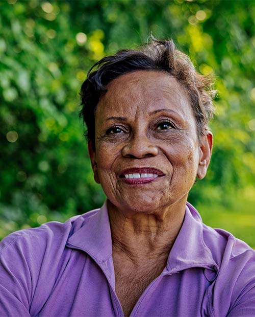 Close-up of a smiling senior woman in a bright purple shirt