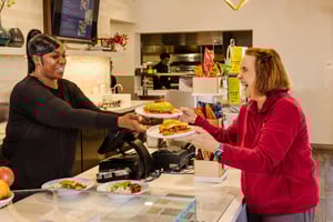 Woman serving lunch to a Regents Point resident