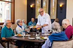 Chef serving food to people at the dinner table
