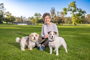 Woman sitting in the grass with her two dogs