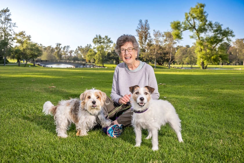 Woman sitting in the grass with her two dogs