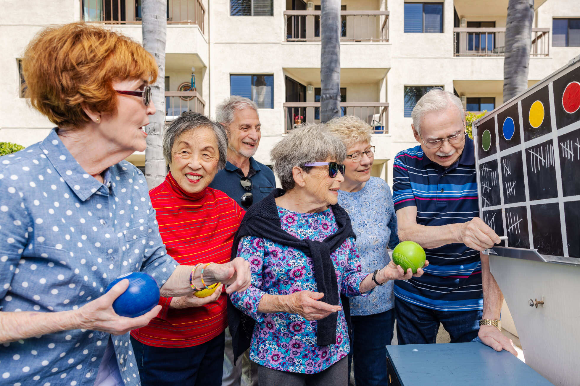 A group of seniors playing lawn bowling outside at Regents Point