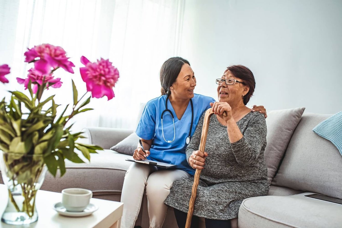 Female medical professional smiling and senior woman with a cane