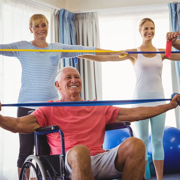 Senior man in a wheelchair using a resistance band in a fitness class