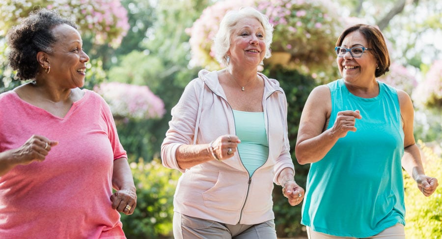 Three senior women walking together outside for fitness