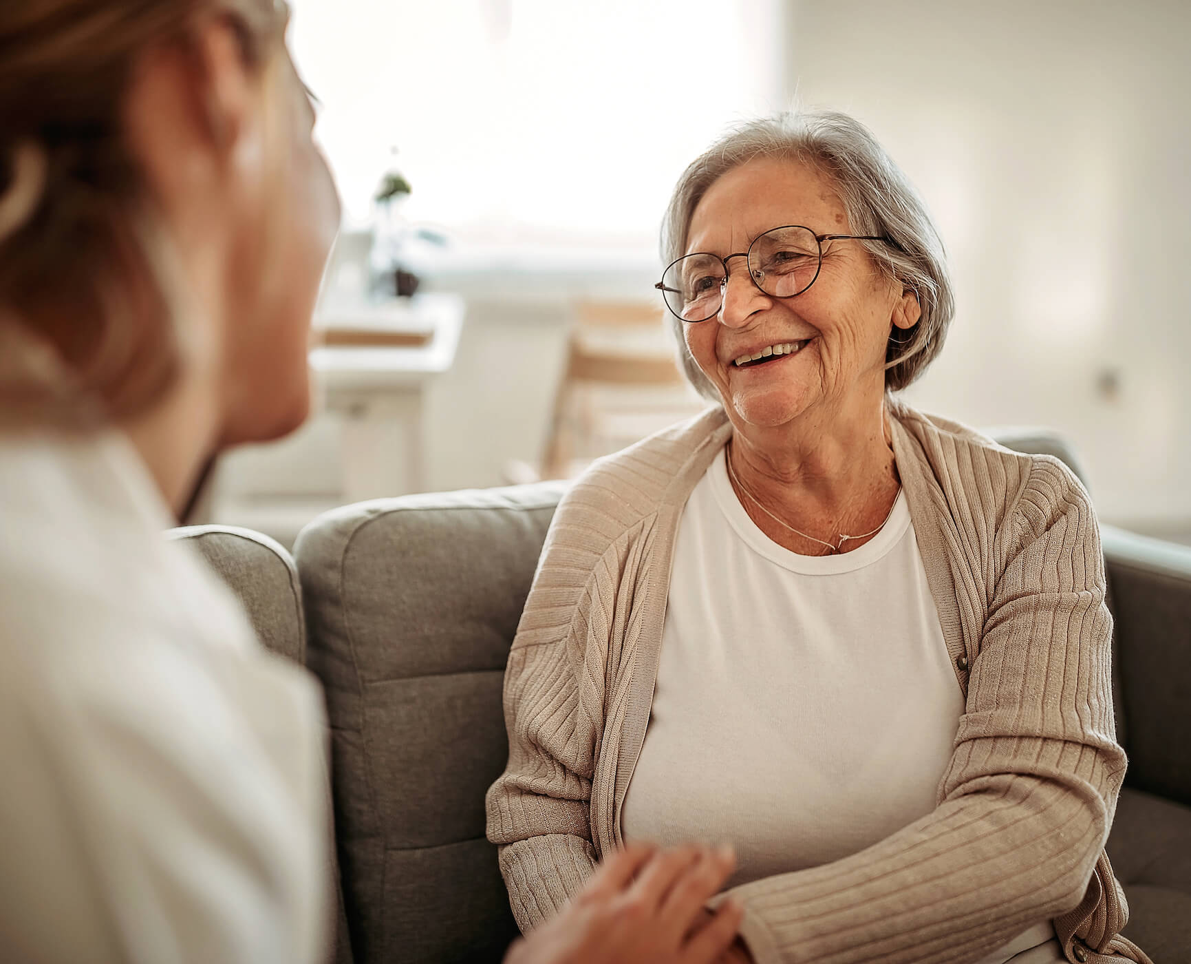 Senior woman sitting on the couch talking to a caregiver