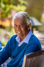 Senior man with white hair sitting on outdoor bench