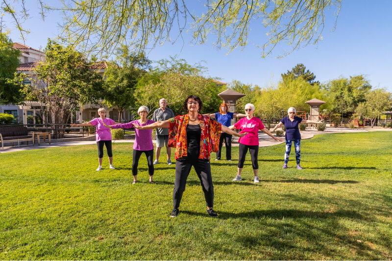Group of seniors taking an outdoor exercise class on the lawn of The Terraces of Phoenix