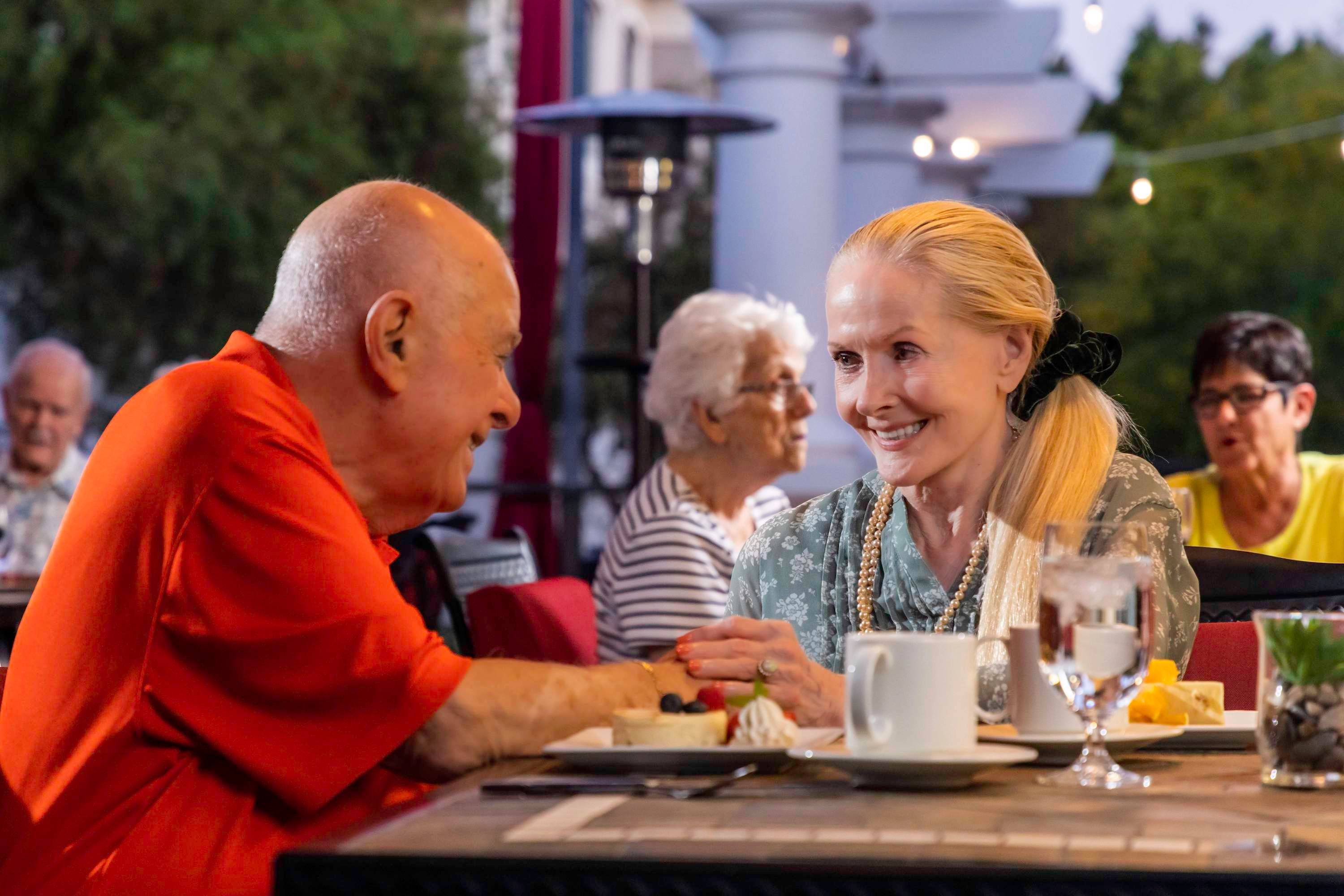 Senior couple holding hands at outdoor dining table