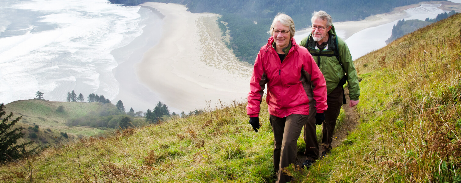 Adventurous senior couple hiking up a hillside next to a beach